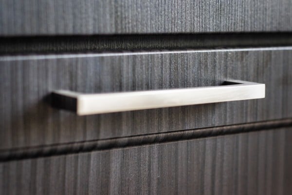 Close-up of modern black and brass cabinet pulls installed on white cabinetry